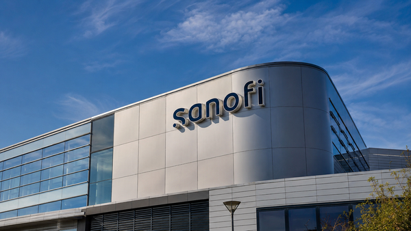 Façade moderne d’un bâtiment Sanofi avec le logo du groupe pharmaceutique sous un ciel bleu.
